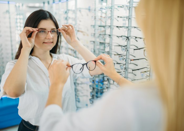Customer trying on spectacle frames at an optical store display